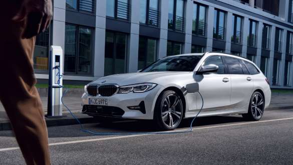 Plug-in hybrid BMW radu 3 Touring 2021 G21 predobočný záber nabíjanie Plug-in hybrid BMW radu 3 Touring 2021 G21 predobočný záber nabíjanie pred budovou