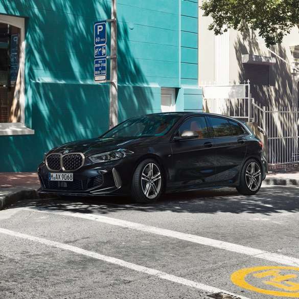 BMW M135i xDrive, trojštvrťový bočný pohľad. Úplne nové BMW M135i xDrive v metalickej farbe Black Sapphire, trojštvrťový bočný pohľad na odparkované vozidlo.