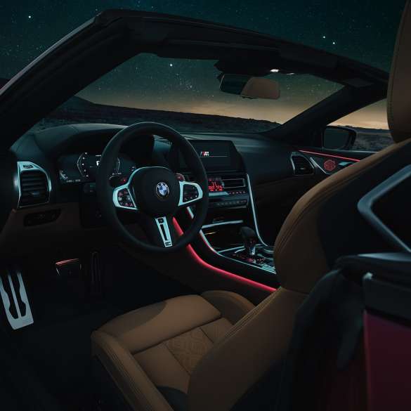 BMW M8 Competition Cabrio, kokpit. BMW M8 Competition Cabrio, kokpit v noci s M koženým volantom a červeným ambientným svetlom.