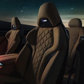 M Sport sedadlá čalúnené kožou Merino. BMW M8 Competition Cabrio s otvorenou strechou pod hviezdnou oblohou, interiér s M Sport sedadlami čalúnenými kožou Merino a červeným ambientným osvetlením.