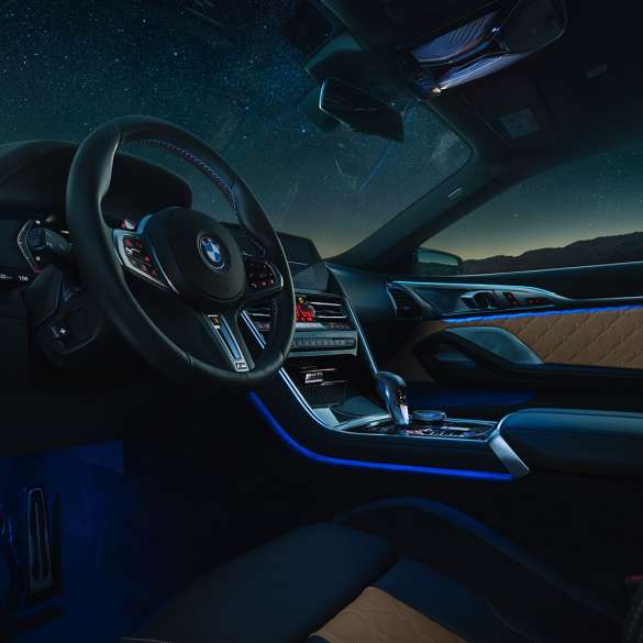 BMW M8 Competition Coupé, kokpit. BMW M8 Competition Coupé, kokpit v noci s M koženým volantom a modrým ambientným svetlom.