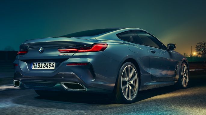 BMW M850i xDrive Coupé, zadný pohľad. BMW M850i xDrive Coupé v metalickej farbe Barcelona Blue, zadný pohľad na vozidlo jazdiace v noci.