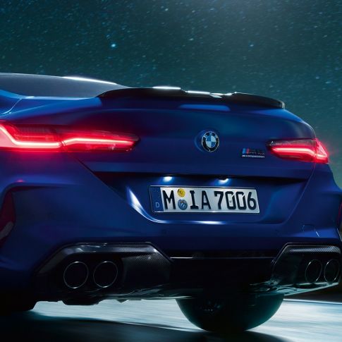 M difúzor v čiernej karbónovej úprave. BMW M8 Competition Coupé v metalickej farbe Marina Bay Blue, detailný zadný pohľad v noci s M difúzorom v čiernej karbónovej úprave.