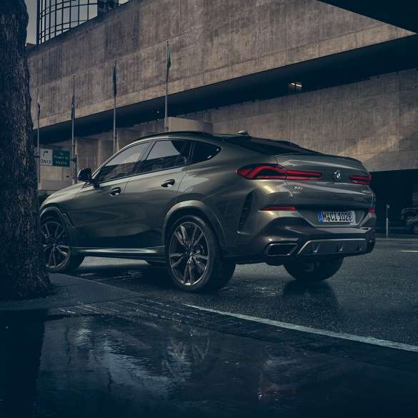 BMW X6 exteriér. BMW X6, trojštvrťový zadný pohľad na vozidlo stojace pred kulisami mesta.