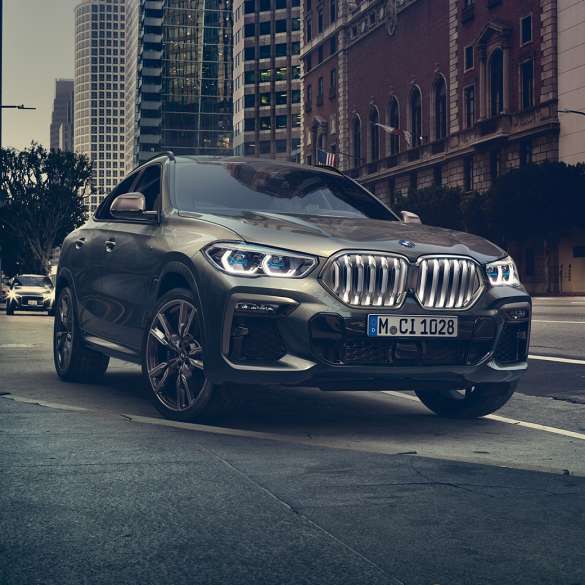 BMW X6 adaptívny M podvozok Professional BMW X6, trojštvrťový predný pohľad na vozidlo stojace pred kulisami mesta.