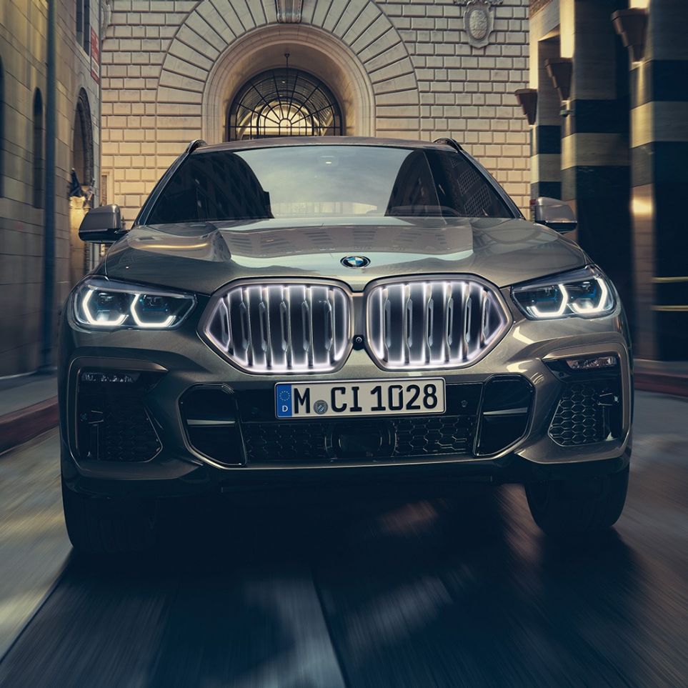 BMW X6 s BMW mriežkou chladiča Iconic Glow. BMW X6 predný pohľad na vozidlo pred kulisami mesta.