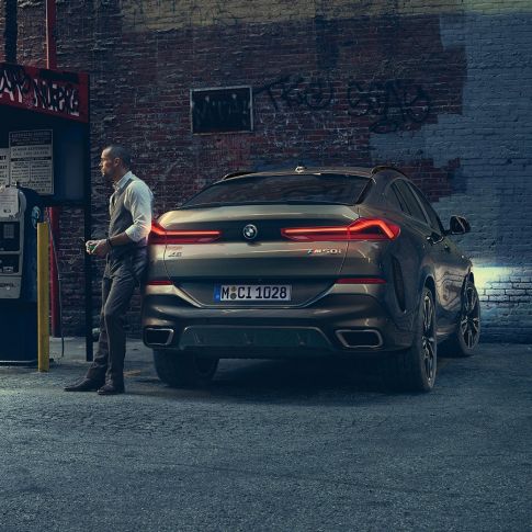 BMW X6 zadná časť. BMW X6, zadný pohľad na vozidlo pred kulisami mesta.