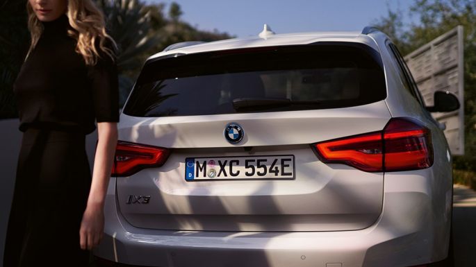 Zadná časť s difúzorom špecifickým pre BMW i BMW iX3 G08 zadný pohľad so ženou Zadná časť s difúzorom špecifickým pre BMW i BMW iX3 G08 2020 metalíza Mineral White zadný pohľad so ženou
