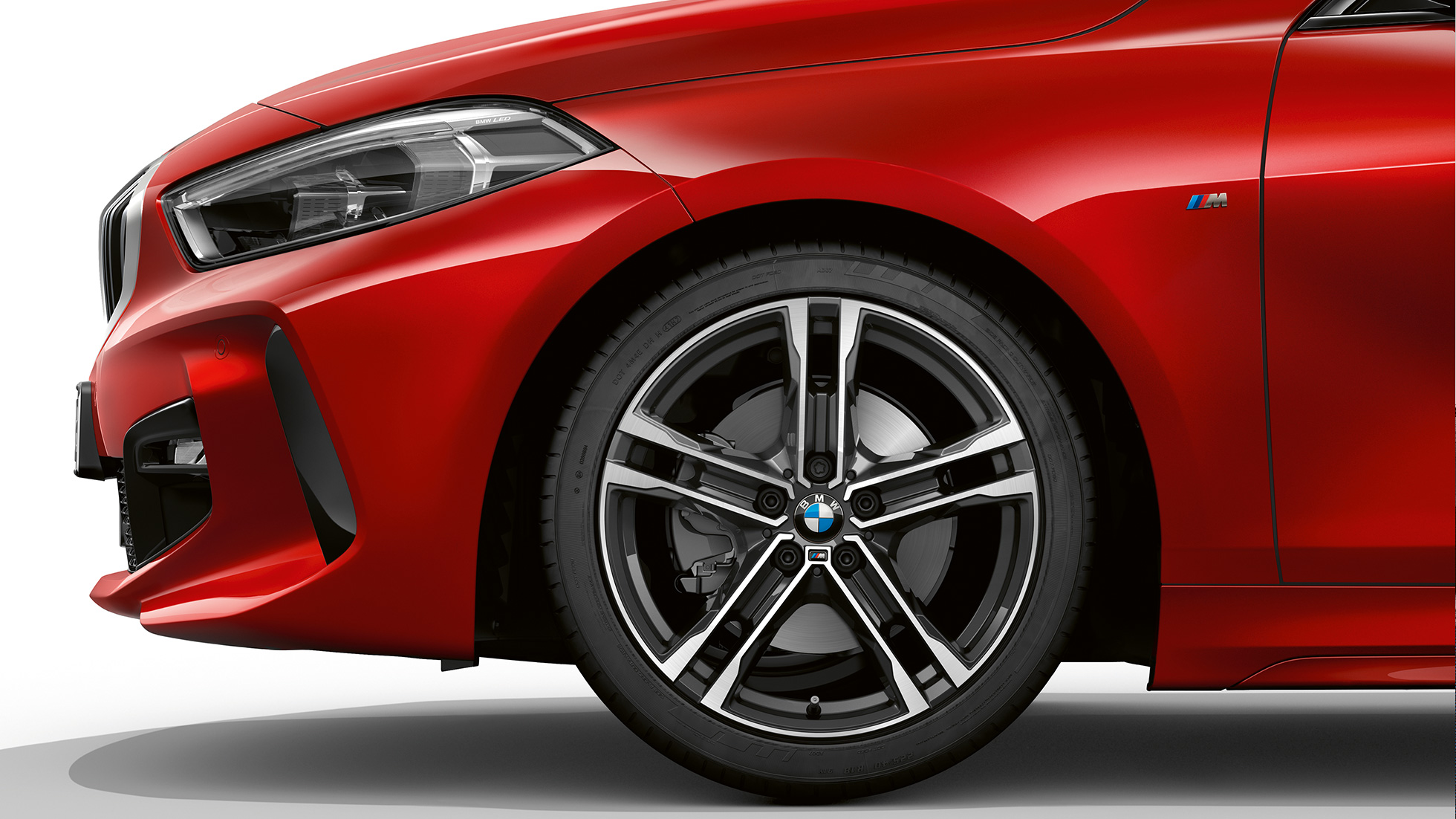 BMW radu 1 Model M Sport, predná strana z boku. BMW radu 1 Model M Sport v metalickej farbe Melbourne Red, predná strana z boku so 17“ diskom kolesa z ľahkej zliatiny Double-spoke 550 M v úprave Bicolour.