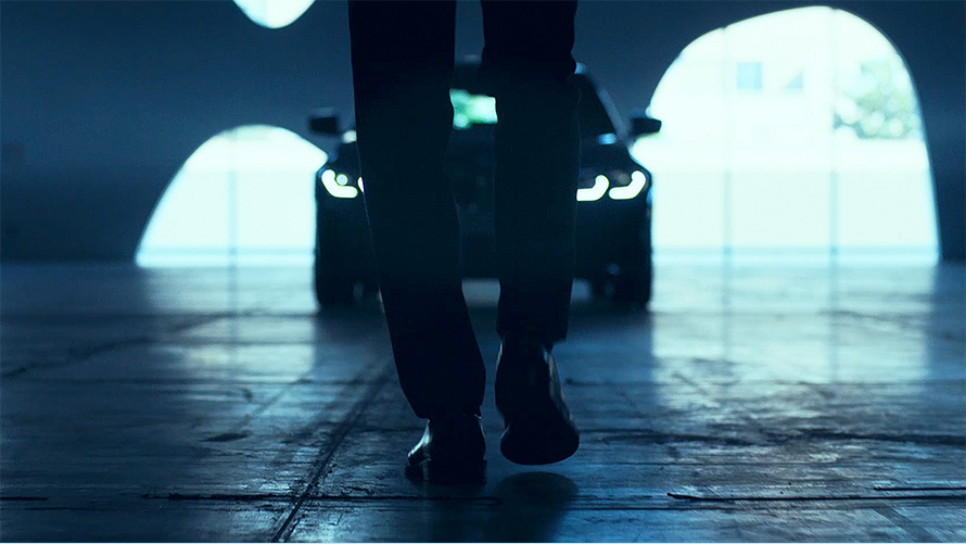BMW radu 3 Sedan (G20), predná časť. Pohľad zozadu na muža kráčajúceho pred BMW radu 3 Sedan (G20) na asfalte.