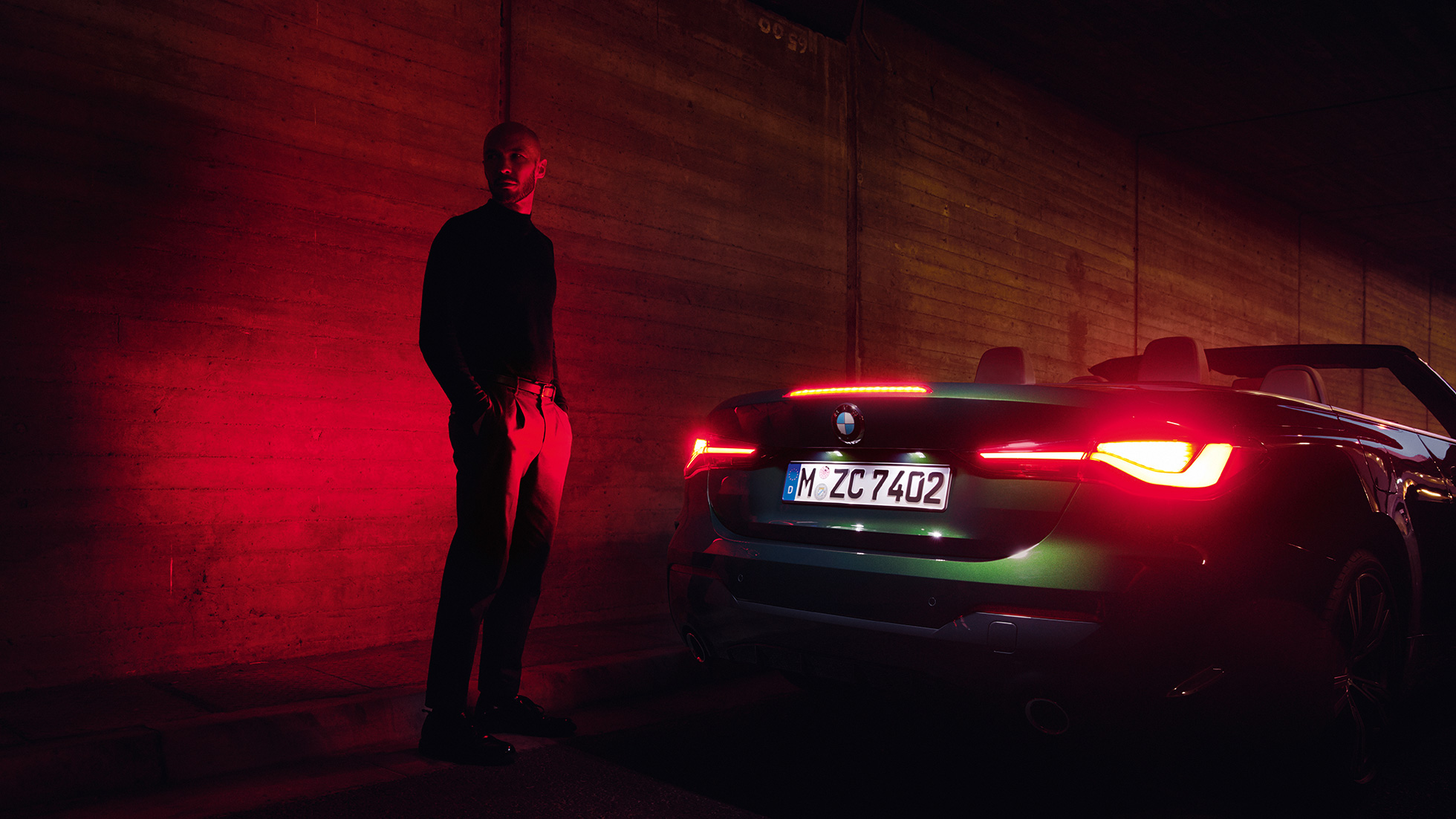 Zadobočný pohľad s otvorenou strechou BMW radu 4 Cabrio G23 2020 BMW radu 4 Cabrio G23 2020 metalíza Sanremo Green zadobočný pohľad v noci s otvorenou strechou.