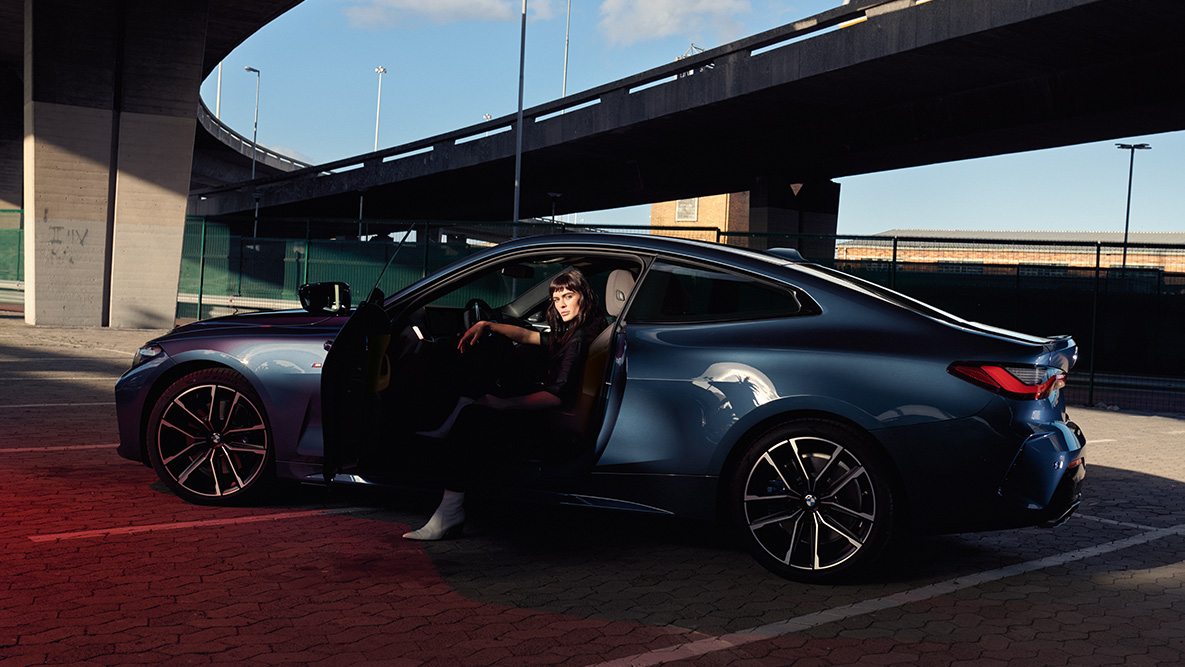 Bočný pohľad disky z ľahkej zliatiny BMW radu 4 Coupé G22 2020 BMW radu 4 Coupé metalíza G22 2020 Arctic Race Blue bočný pohľad disky z ľahkej zliatiny modelka v aute otvorené dvere