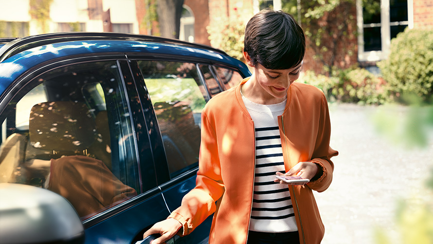 BMW servis Žena so smartfónom pri dverách svojho BMW BMW servis Žena so smartfónom pri dverách svojho BMW