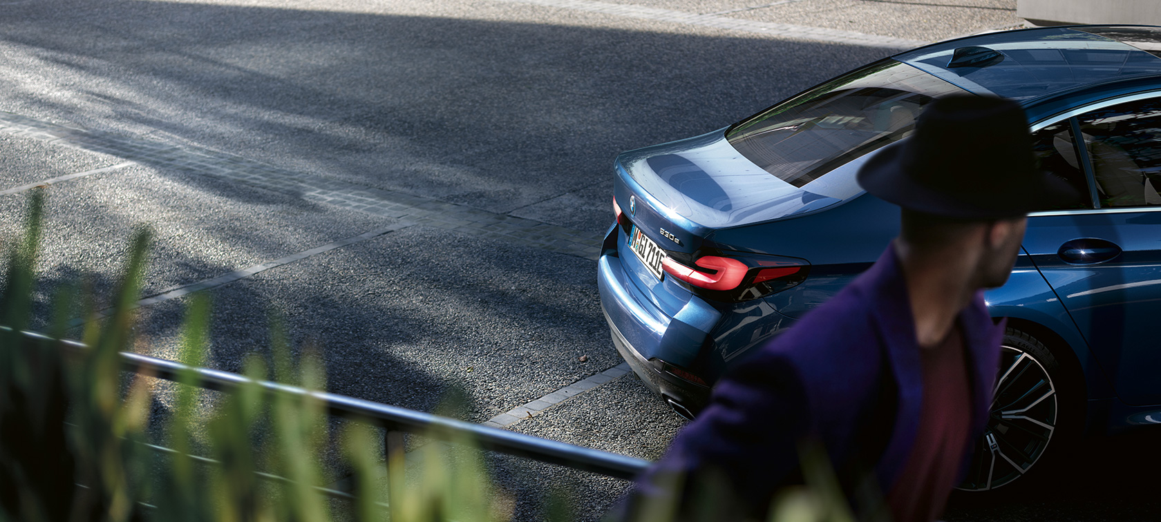 Muž stojaci za zaparkovaným BMW BMW radu 5 Sedan G30 BMW radu 5 Sedan G30 Facelift 2020 muž stojaci za zaparkovaným BMW