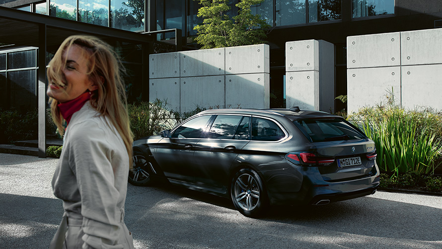BMW radu 5 Touring G31 LCI v metalíze Sophisto Grey s briliantovým efektom bočný pohľad Žena pred zaparkovaným BMW radu 5 Touring G31 facelift 2020 v metalíze Sophisto Grey s briliantovým efektom bočný pohľad