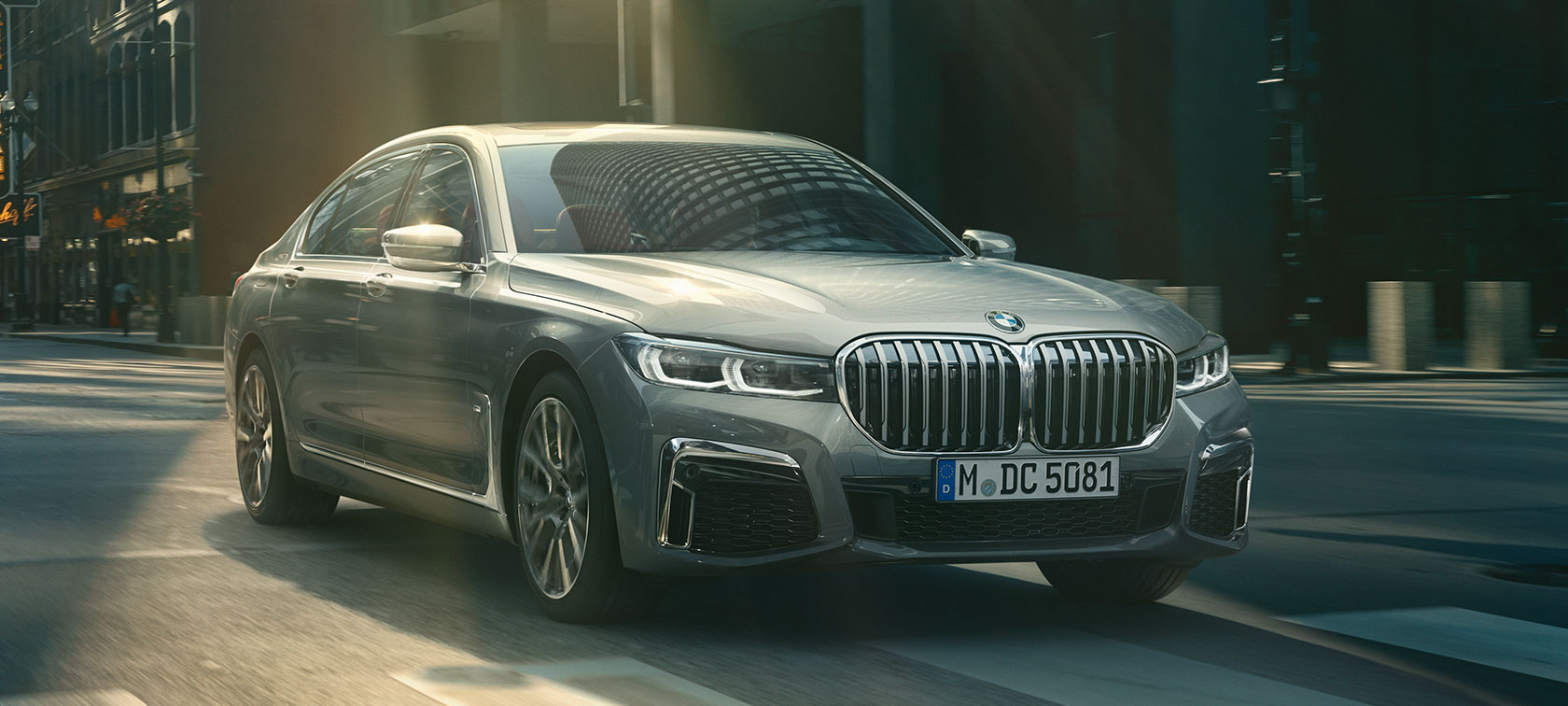 Sivé BMW radu 7 Sedan počas jazdy, trojštvrťový pohľad spredu Sivé BMW radu 7 Sedan jazdiace mestským prostredím v trojštvrťovom pohľade spredu