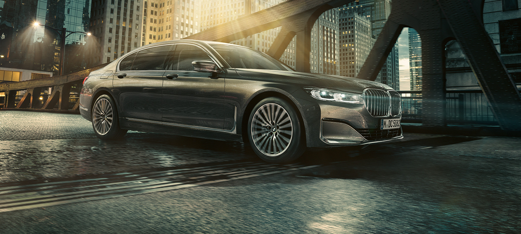 BMW radu 7 Sedan G11 G12 2019 bočný pohľad BMW radu 7 Sedan G11 G12 2019 Bernina Grey s jantárovým efektom predobočný pohľad v mestskom prostredí