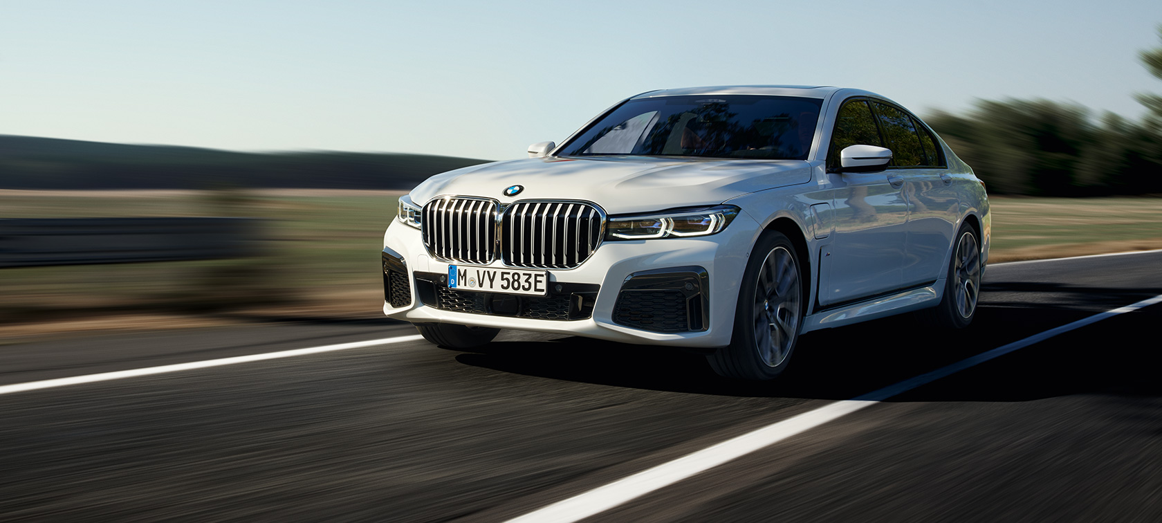 BMW 745e Sedan plug-in hybrid G11 G12 metalíza Mineral White predobočný pohľad BMW 745e Sedan plug-in hybrid G11 G12 metalíza Mineral White predobočný pohľad jazdný na vidieckej ceste