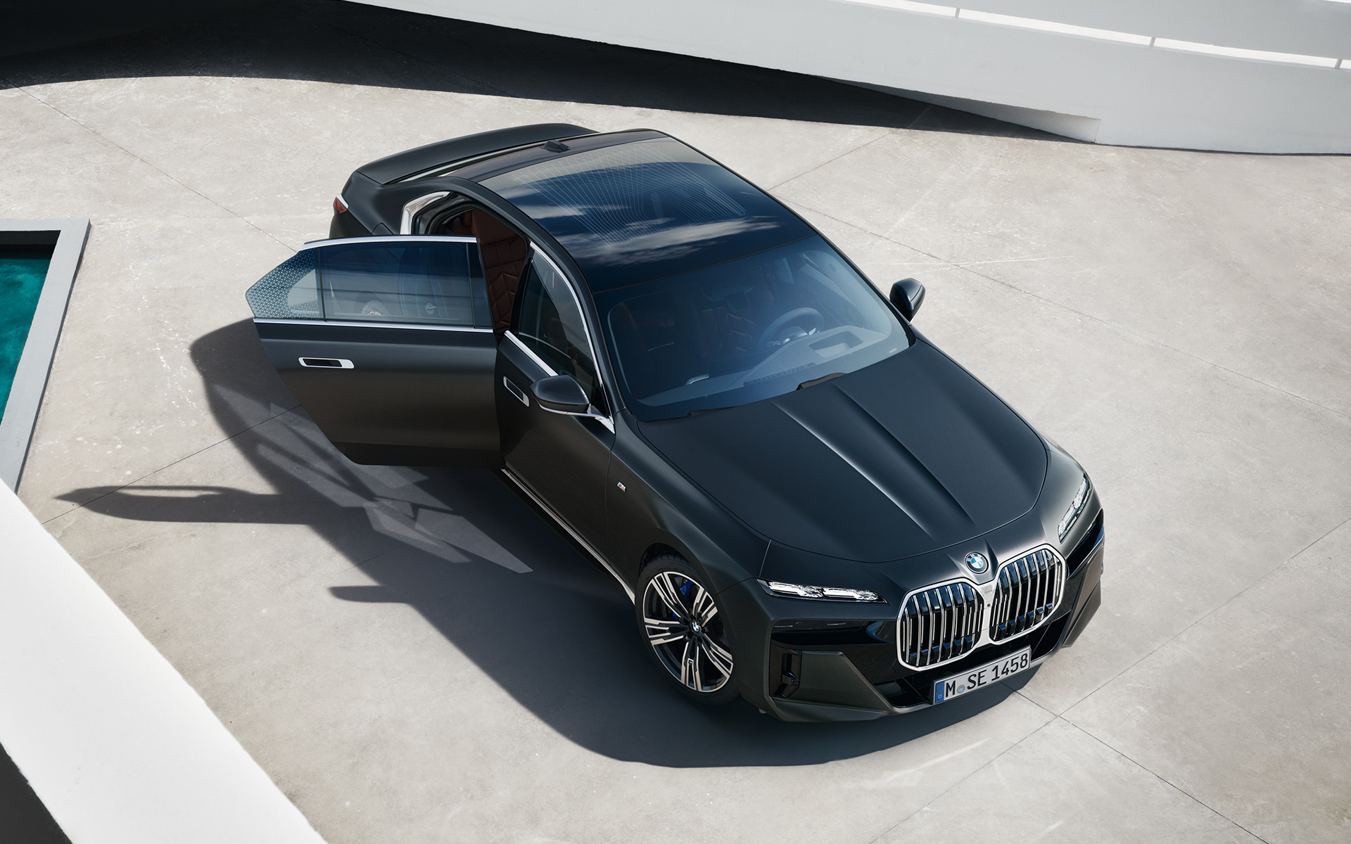 Pohľad zhora BMW radu 7 Sedan G70 ICE M Sport balík metalíza Frozen Deep Grey BMW radu 7 Sedan G70 ICE 740i M Sport balík metalíza Frozen Deep Grey pohľad zhora s otvorenými dverami spolujazdca