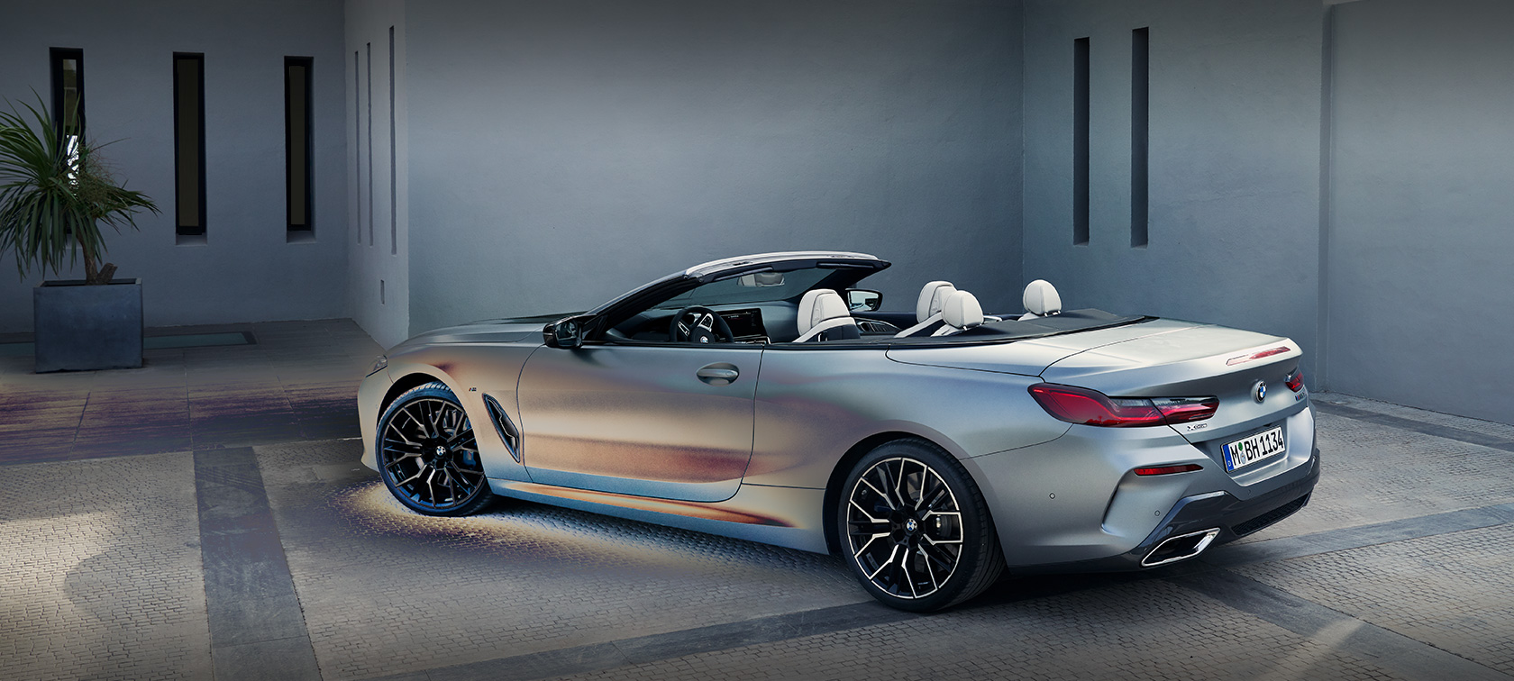 Muž sa opiera o BMW radu 8 Cabrio G14 Facelift 2022 BMW Individual metalíza Frozen Pure Grey bočný pohľad statický pred budovou s modelom