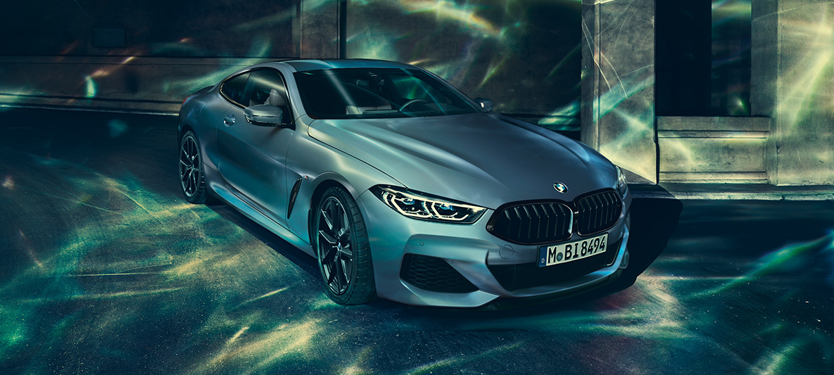 BMW M850i Coupé First Edition, trojštvrťový pohľad spredu Trojštvrťový predný pohľad na stojace BMW M850i Coupé First Edition pred kulisami mesta.