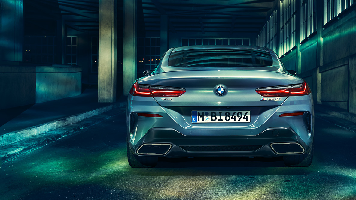 BMW radu 8 Coupé, zadný záber. Zadný záber BMW radu 8 Coupé pred kulisou nočného mesta.