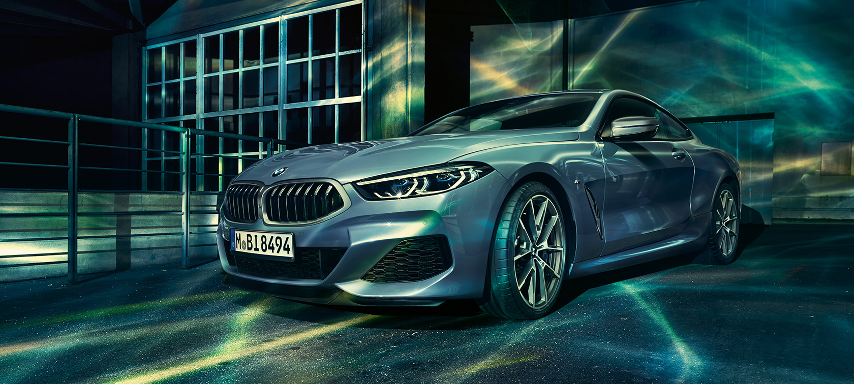 BMW radu 8 Coupé, predobočný záber. BMW radu 8 Coupé, predobočný záber, pred industriálnou budovou.