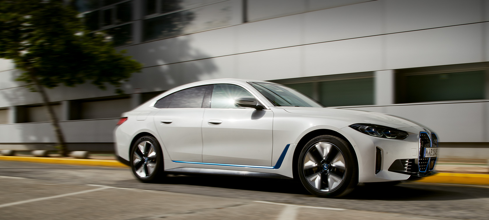 BMW i4 eDrive40 G26 2021 bočný pohľad jazdný pred budovou BMW i4 eDrive40 G26 2021 bočný pohľad jazdný pred budovou