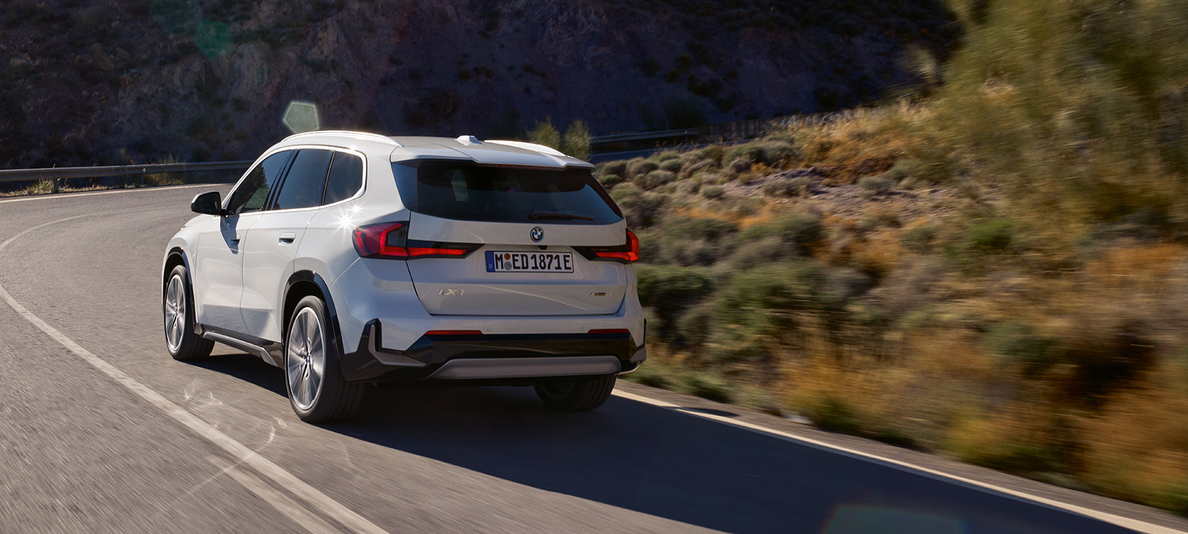 BMW iX1 U11 BEV jazdná dynamika to najlepšie video BMW iX1 U11 BEV 2022 metalíza Mineral White zadobočný pohľad jazdný na horskej ceste jazdná dynamika to najlepšie video