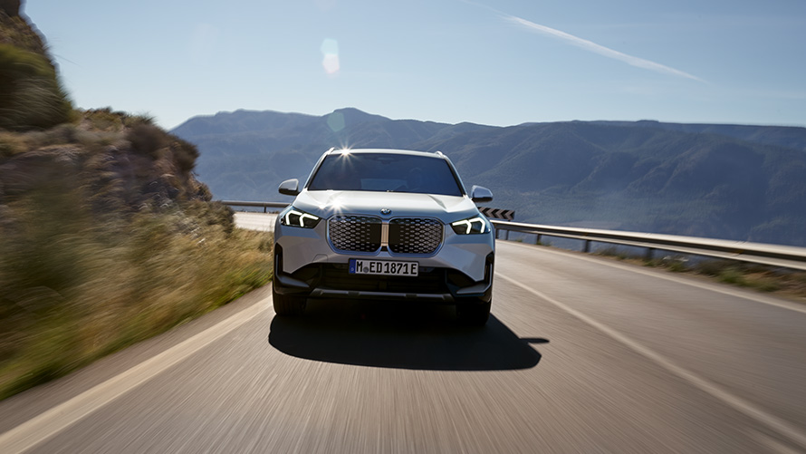 BMW iX1 U11 BEV 2022 predný pohľad BMW iX1 U11 BEV 2022 metalíza Mineral White predný pohľad jazdný na horskej ceste
