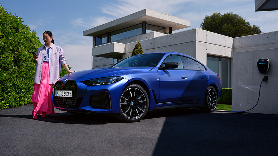 BMW i4 M50 G26 2021 BMW Individual metalíza Frozen Portimao Blue predobočný pohľad statický so ženou pred domom