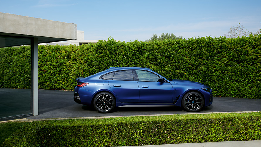Zadný pohľad BMW i4 M50 G26 2021 jazda na vidieckej ceste BMW i4 M50 G26 2021 BMW Individual metalíza Frozen Portimao Blue zadný záber jazdný na vidieckej ceste