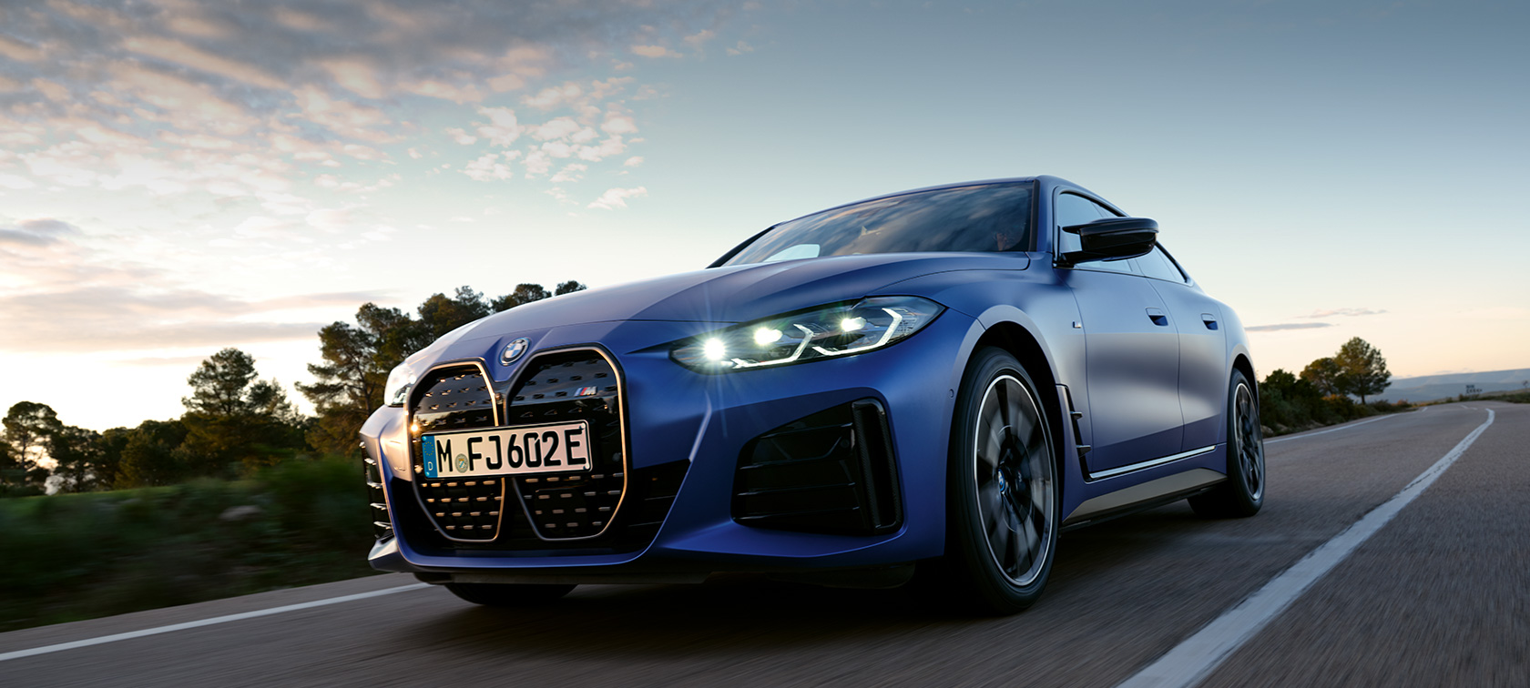 BMW i4 M50 G26 2021 bočný pohľad statický pred kamenistým terénom BMW i4 M50 G26 2021 BMW Individual metalíza Frozen Portimao Blue bočný pohľad statický pred kamenistým terénom