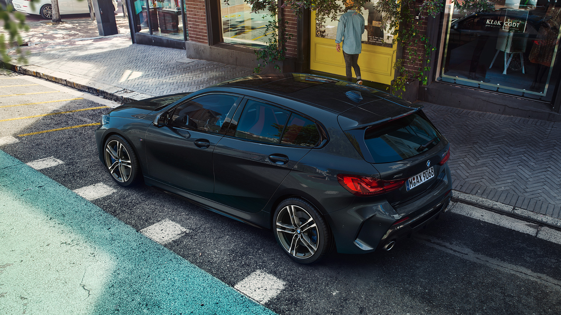 BMW M135i xDrive, odparkované. BMW M135i xDrive v metalickej farbe Black Sapphire, odparkované, pohľad z vtáčej perspektívny na bočnú časť.