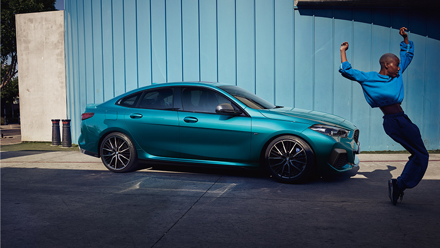 BMW M235i xDrive Gran Coupé F44 bočný pohľad so ženou BMW M235i xDrive Gran Coupé F44 metalíza Snapper Rocks Blue bočný pohľad so ženou