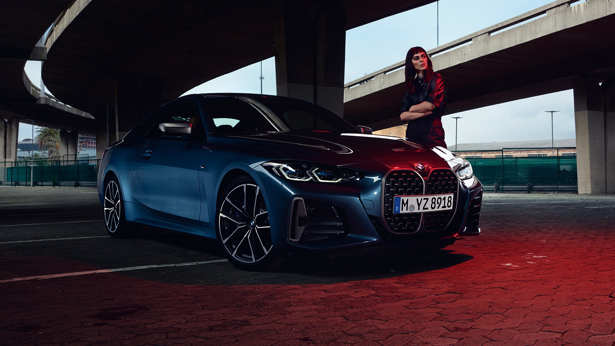Modelka stojaca pri BMW M440i xDrive Coupé G22 2020 bočný pohľad BMW M440i xDrive Coupé metalíza Arctic Race Blue G22 2020 bočný pohľad s modelkou