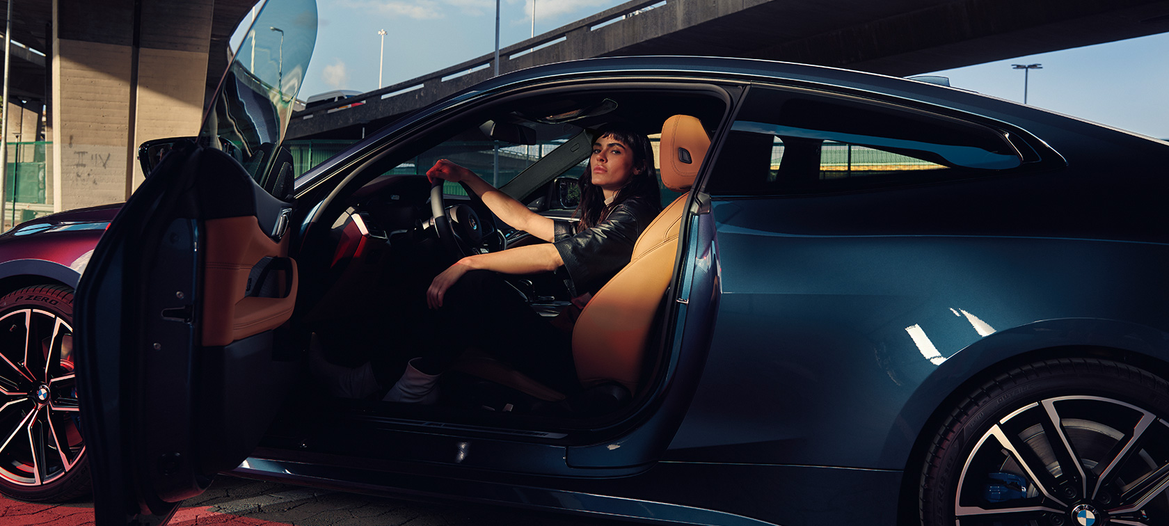 Bočný pohľad a modelka BMW M440i xDrive Coupé G22 2020 BMW M440i xDrive Coupé G22 2020 metalíza Arctic Race Blue bočný pohľad a modelka v aute otvorené dvere