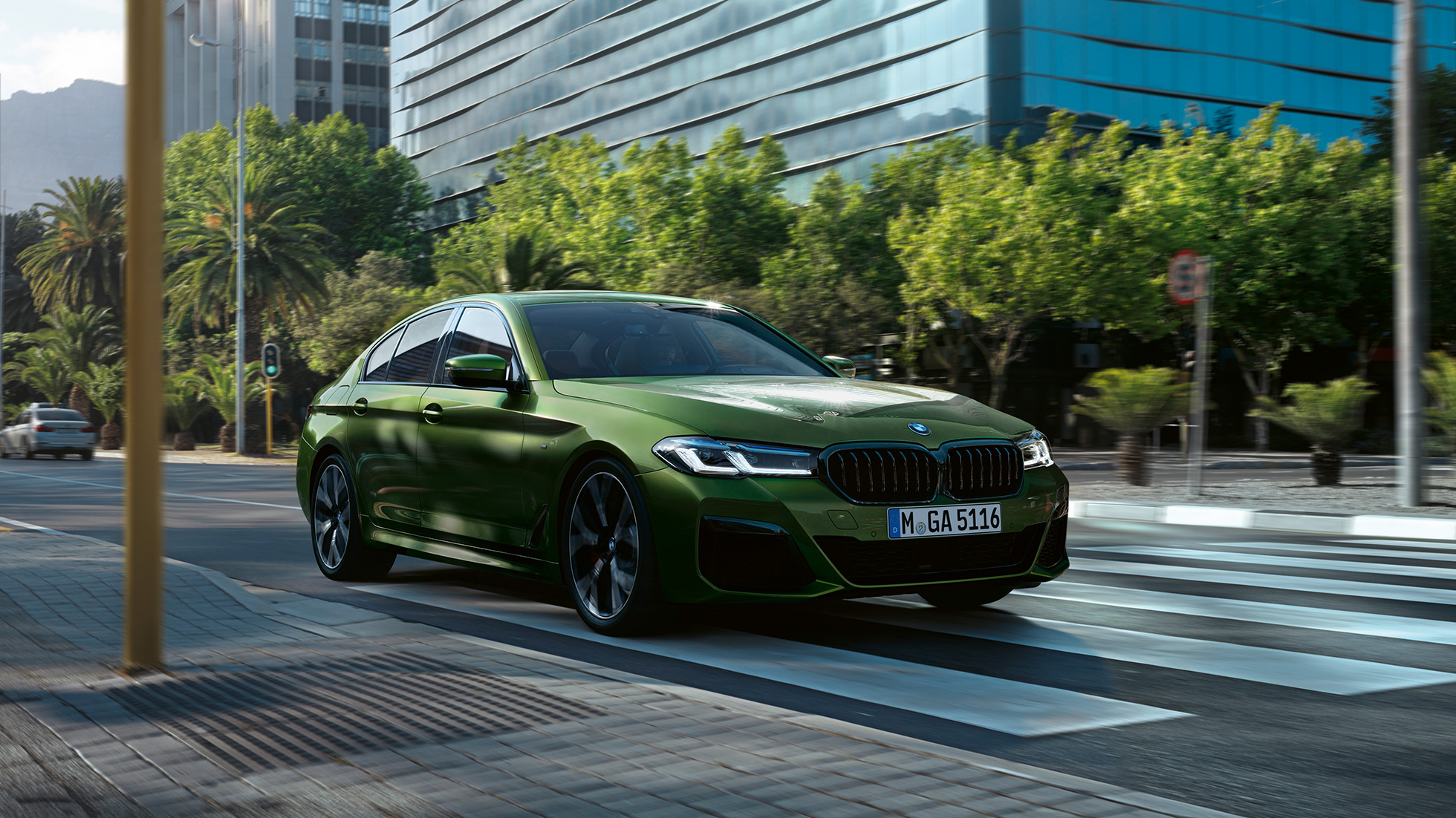 BMW M550i xDrive Sedan G30 LCI Facelift 2020 predobočný pohľad jazdný BMW M550i xDrive Sedan G30 LCI Facelift 2020 BMW Individual metalíza Verde Ermes predobočný jazdný pohľad v meste