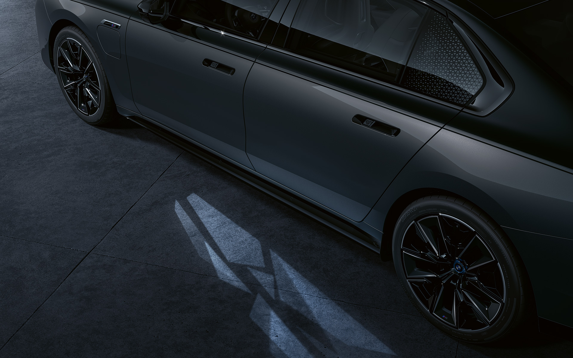 Koncepcia osvetlenia BMW M760e xDrive Sedan G70 BMW Individual dvojfarebná metalíza Black Sapphire Dravite Grey detailný pohľad s aktivovanou funkciou Welcome Light Carpet