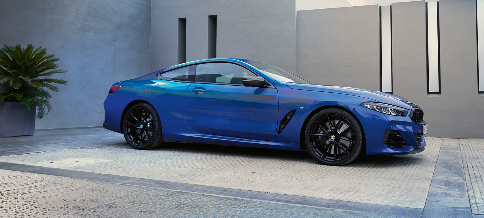 Bočný pohľad BMW M850i xDrive Coupé G15 LCI Facelift 2022 BMW M850i xDrive Coupé G15 LCI Facelift 2022 metalíza M Portimao Blue bočný pohľad statický pred budovou