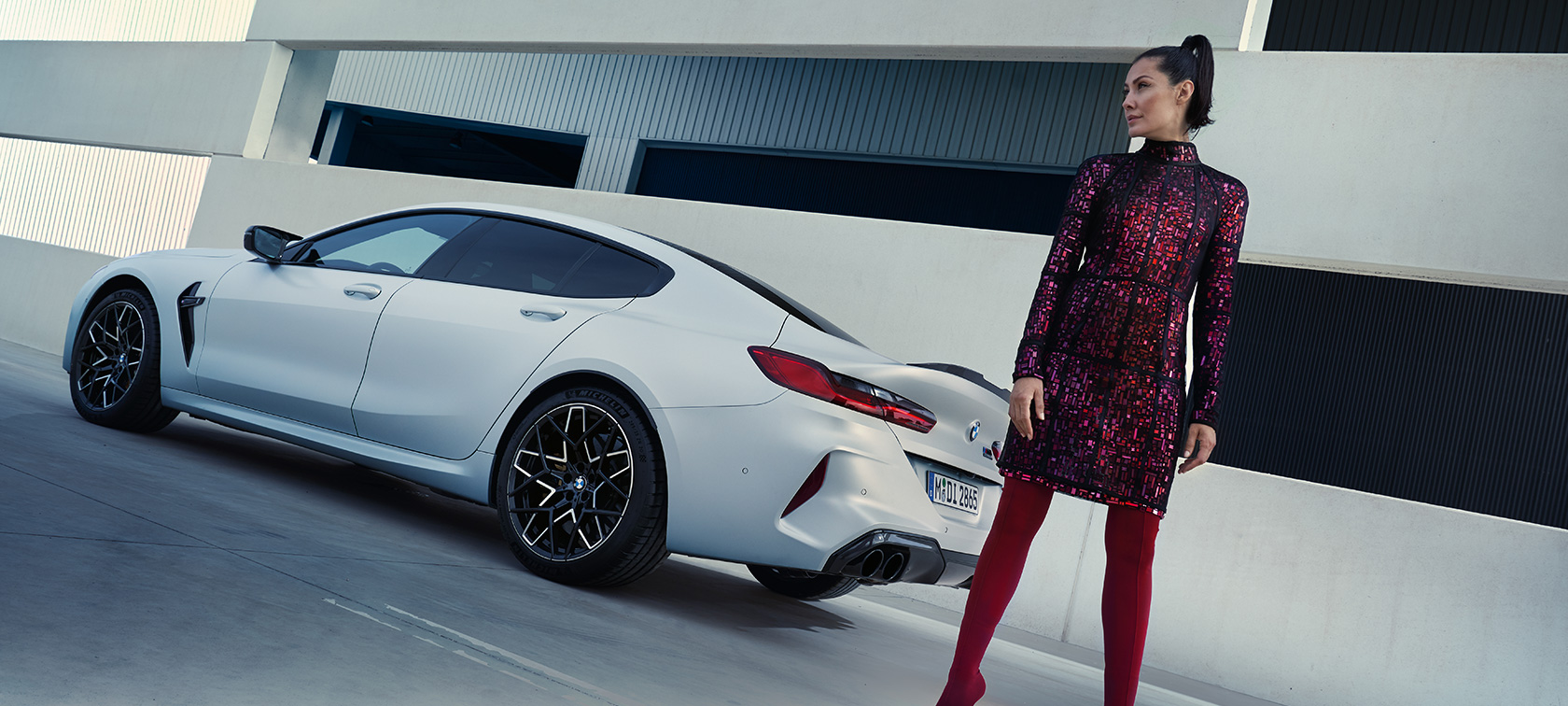 Zadobočný pohľad BMW M8 Competition Gran Coupé F93 LCI 2022 BMW M8 Competition Gran Coupé F93 LCI Facelift 2022 BMW Individual metalíza Frozen Brilliant White zadobočný pohľad s modelkou stojacou pri vozidle