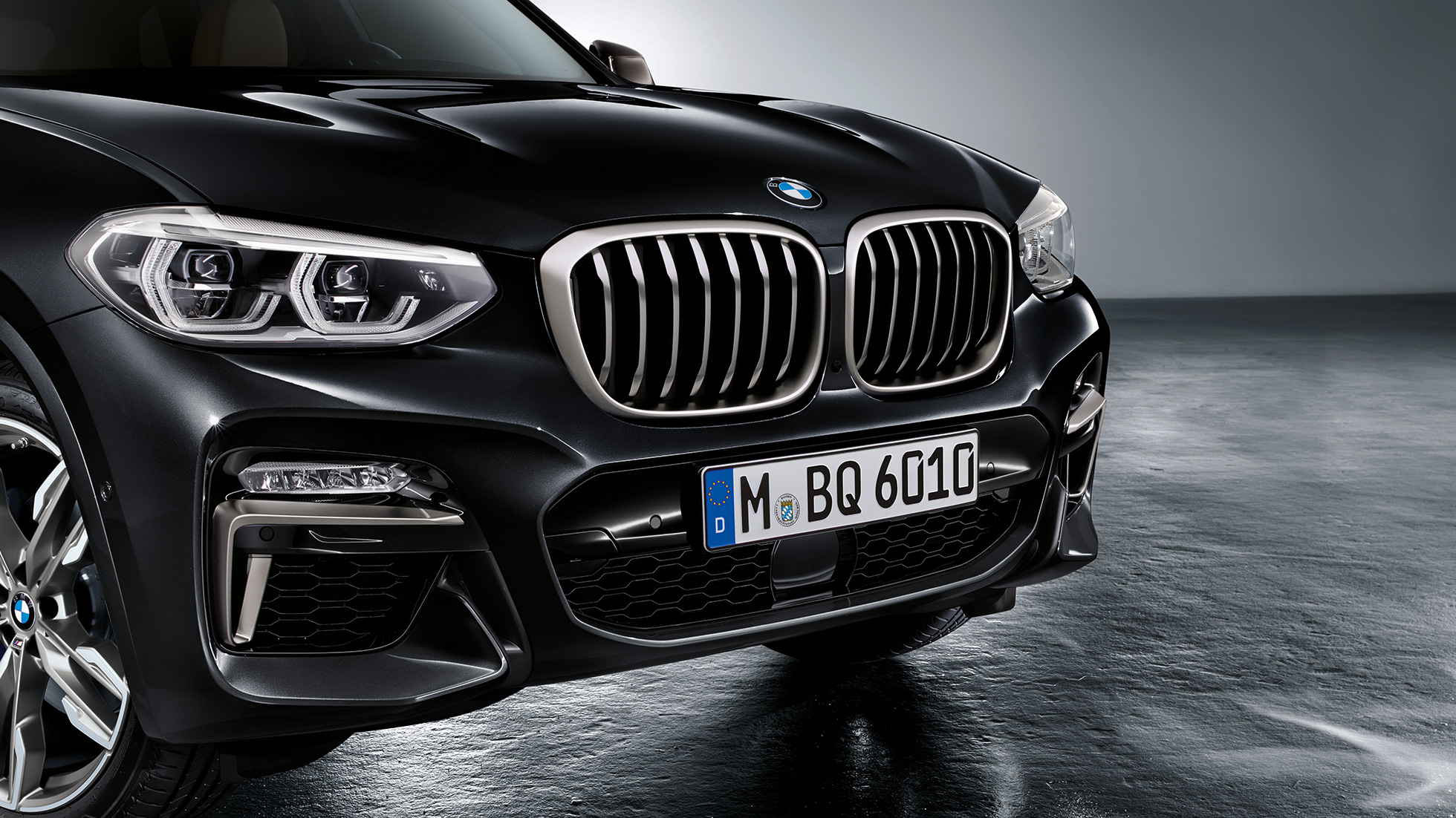 BMW X3 M40i a BMW X3 M40d, predná časť. BMW X3 M40i a BMW X3 M40d v metalickej farbe Black Sapphire, exteriér, predná časť s dizajnovými prvkami vo farbe Cerium Grey.