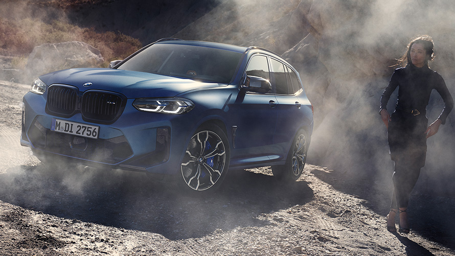 BMW X3 M Competition F97 LCI 2021 predobočný záber statický v kamenistom teréne BMW X3 M Competition F97 LCI Facelift 2021 metalíza Frozen Marina Bay Blue predobočný záber statický v kamenistom teréne s modelkou