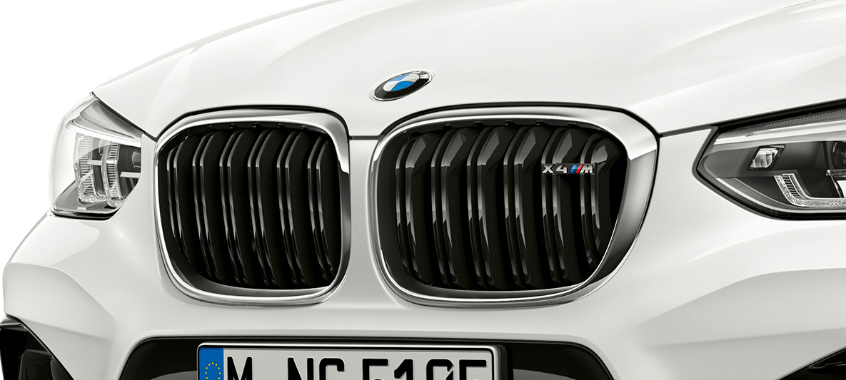 BMW X4 M, M mriežka chladiča. BMW X4 M vo farbe Alpine White, exteriér, predná časť, M mriežka chladiča s chrómovými prvkami a označením modelu.