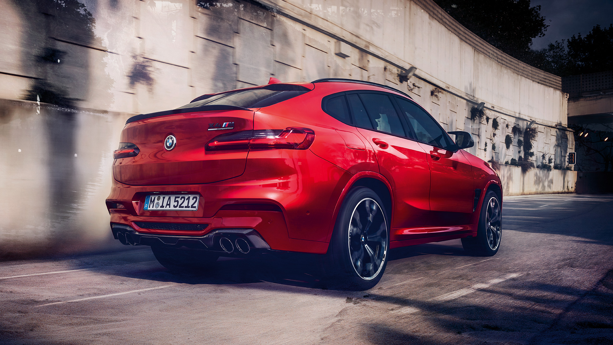 BMW X4 M Competition, bočný zadný pohľad. BMW X4 M Competition v metalickej farbe Toronto Red, exteriér, bočný zadný pohľad.
