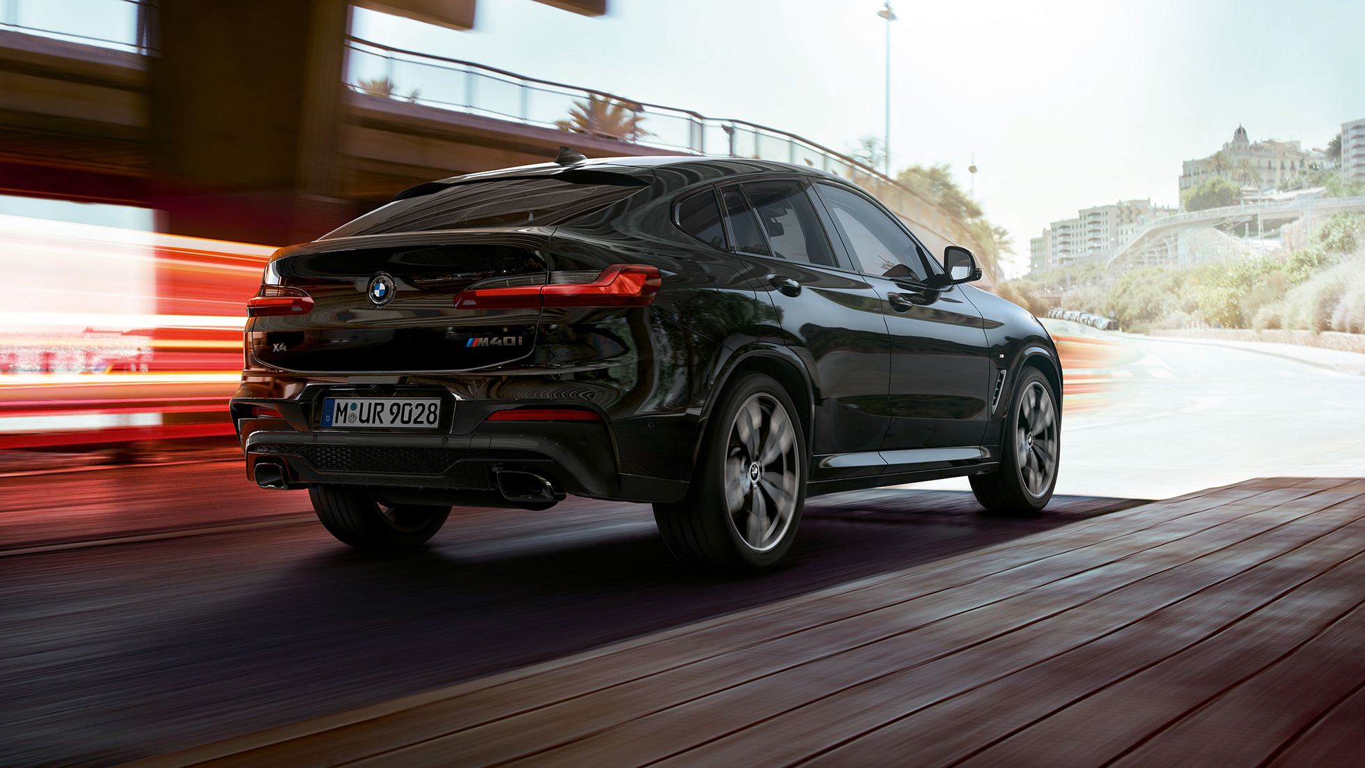 BMW X4 M40i, trojštvrťový zadný pohľad. BMW X4 M40i v metalickej farbe Black Sapphire, exteriér, trojštvrťový zadný pohľad, pravá strana so svetelnými pásmi.