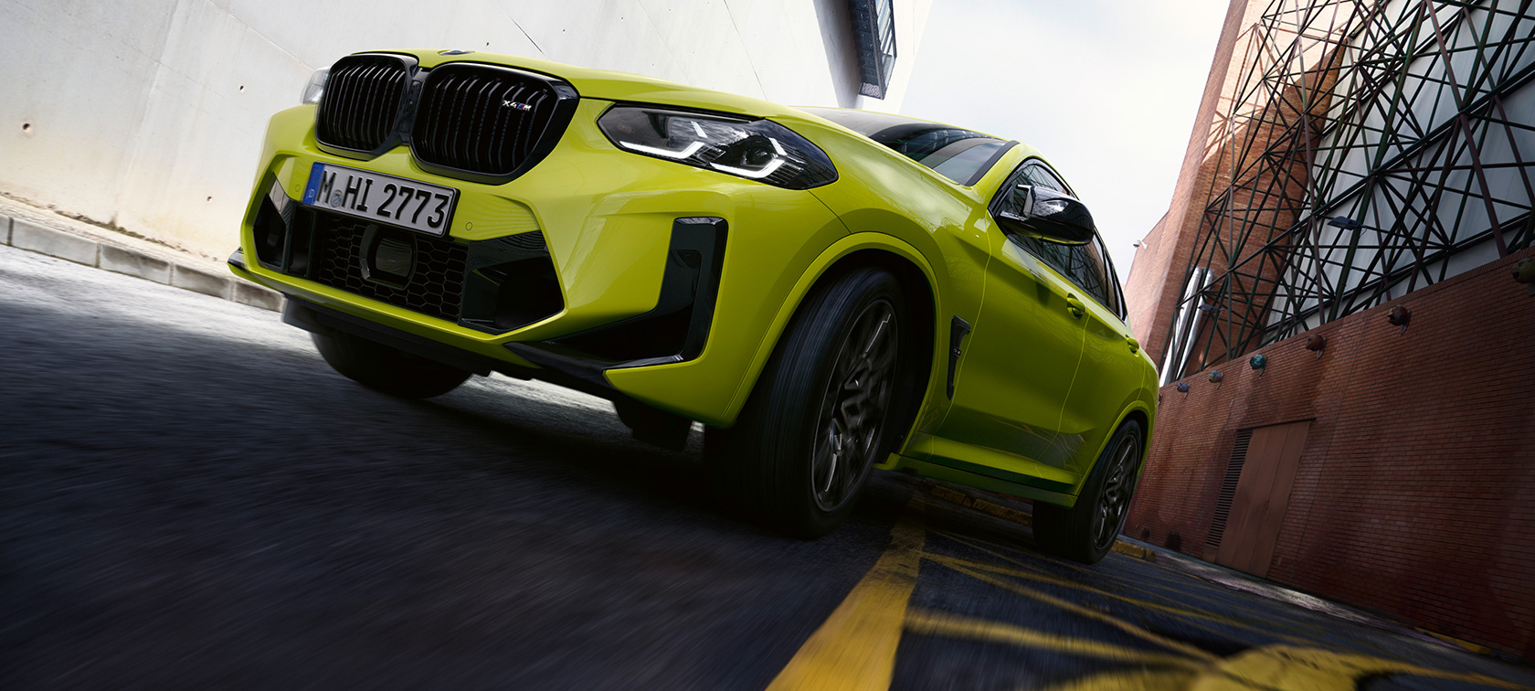 Predobočný pohľad záber zdola BMW X4 M Competition F98 LCI 2021 BMW X4 M Competition F98 LCI Facelift 2021 Sao Paulo Yellow predobočný záber zdola jazda medzi domami.
