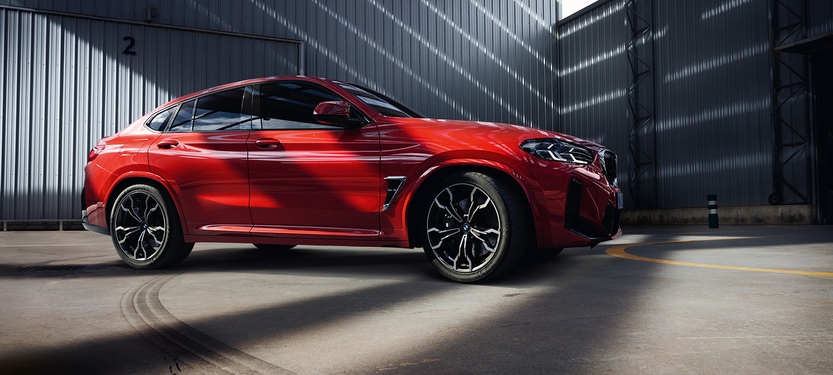 Predobočný pohľad BMW X4 M F98 LCI Facelift 2021 BMW X4 M F98 LCI Facelift 2021 metalíza Toronto Red predobočný pohľad v továrenskej hale