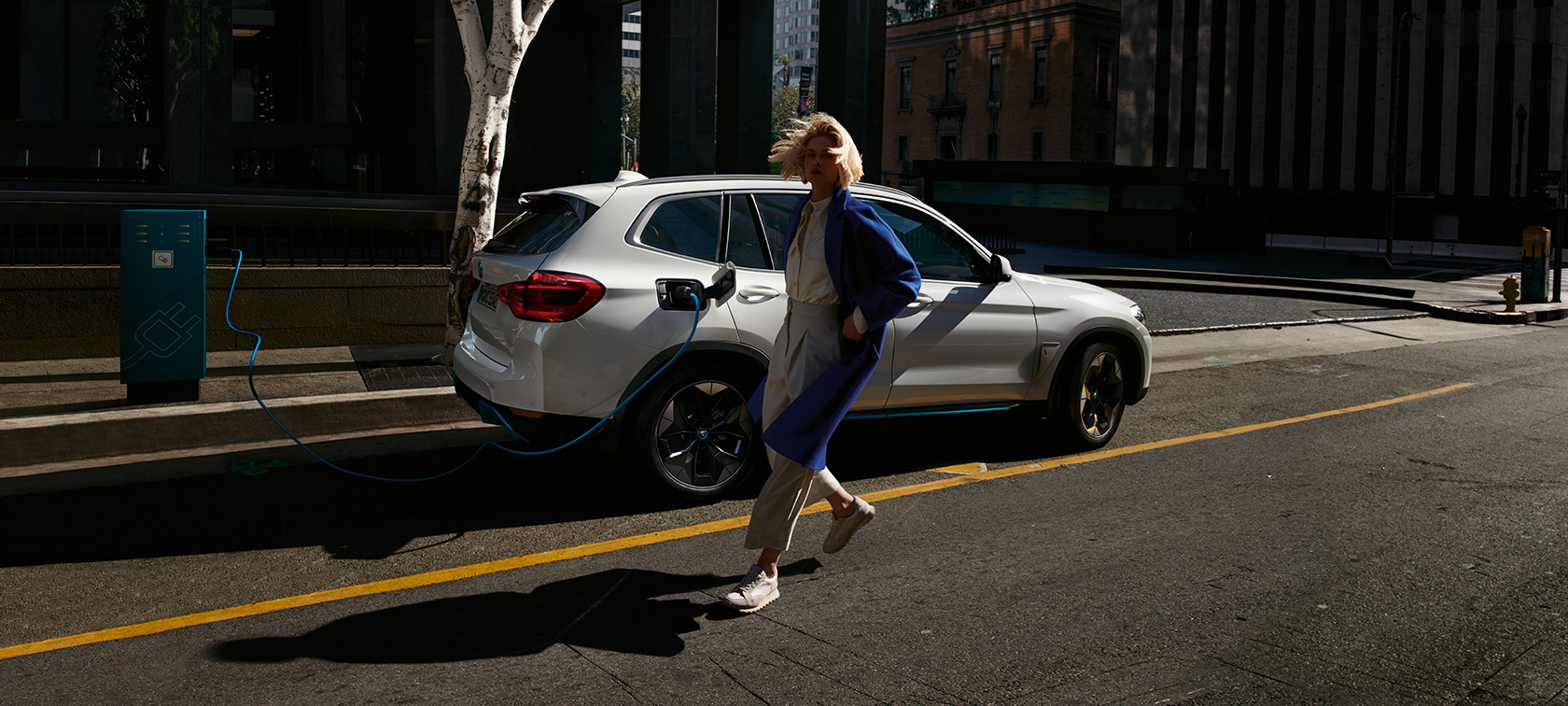 BMW iX3 G08 na verejnej nabíjacej stanici bočný pohľad BMW iX3 G08 2020 metalíza Mineral White na verejnej nabíjacej stanici bočný pohľad
