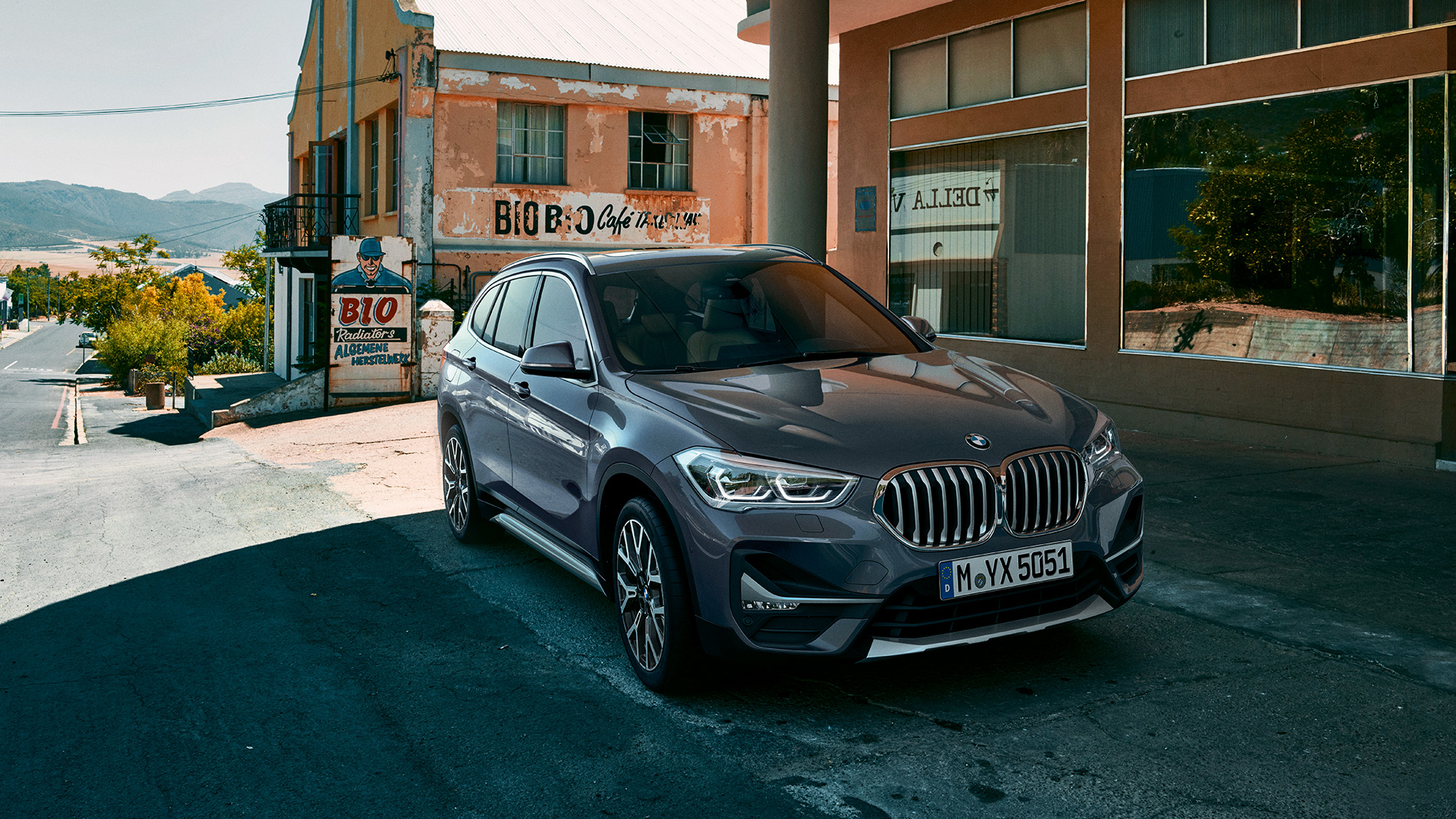 BMW X1, trojštvrťový predný pohľad. BMW X1, trojštvrťový predný pohľad na vozidlo stojace pred kulisami mesta.